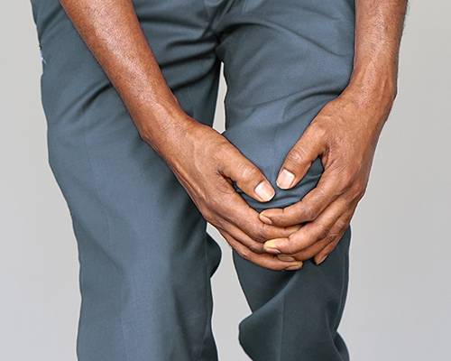 african american holding painful gout knee