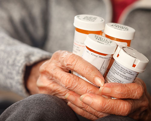 elderly woman holding prescription bottles
